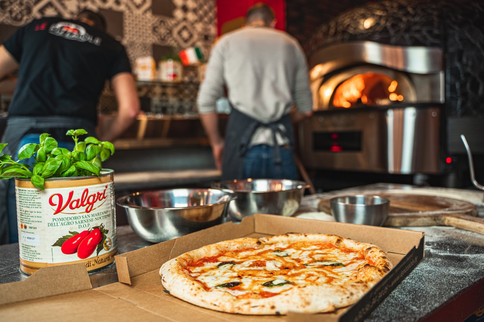 Pizza margherita fraîche sortie du four, avec du basilic et des tomates San Marzano en arrière-plan